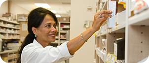 pharmacist reaching for medication on a shelf
